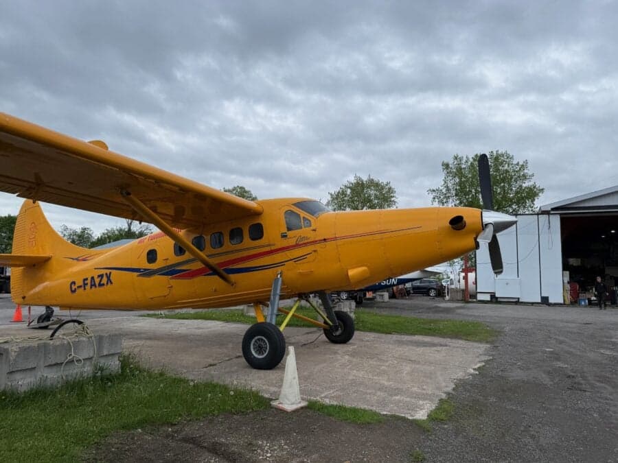 Yellow aircraft parked on the ground near a hangar.