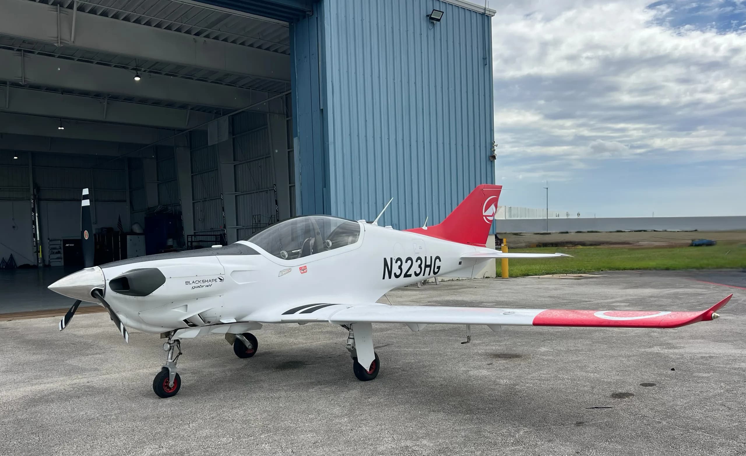 A Blackshape Gabriel aircraft with registration N323HG parked outside a hangar.