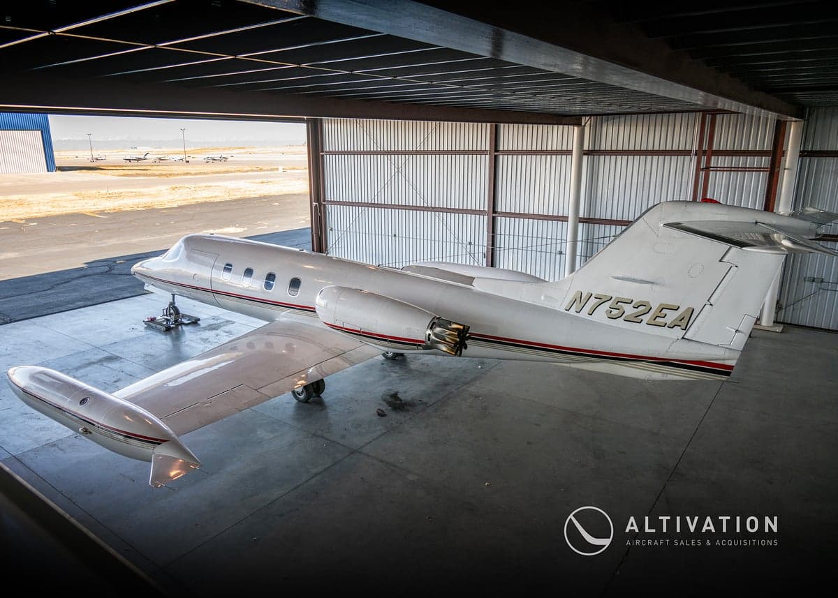 A Learjet in a hangar with the door open.