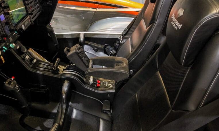 The interior of a Diamond DA62 aircraft features black leather seats and a center console.