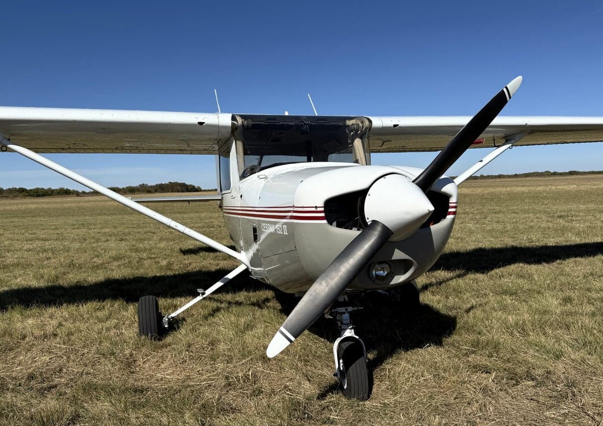 Front view of a Cessna 152 II aircraft on a grassy field.