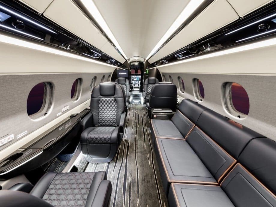 A view of the interior cabin of a private jet with leather seats and wood trim.