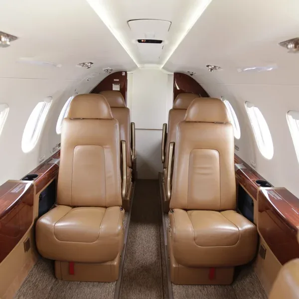 A private jet cabin interior featuring tan leather seats arranged in a club configuration.