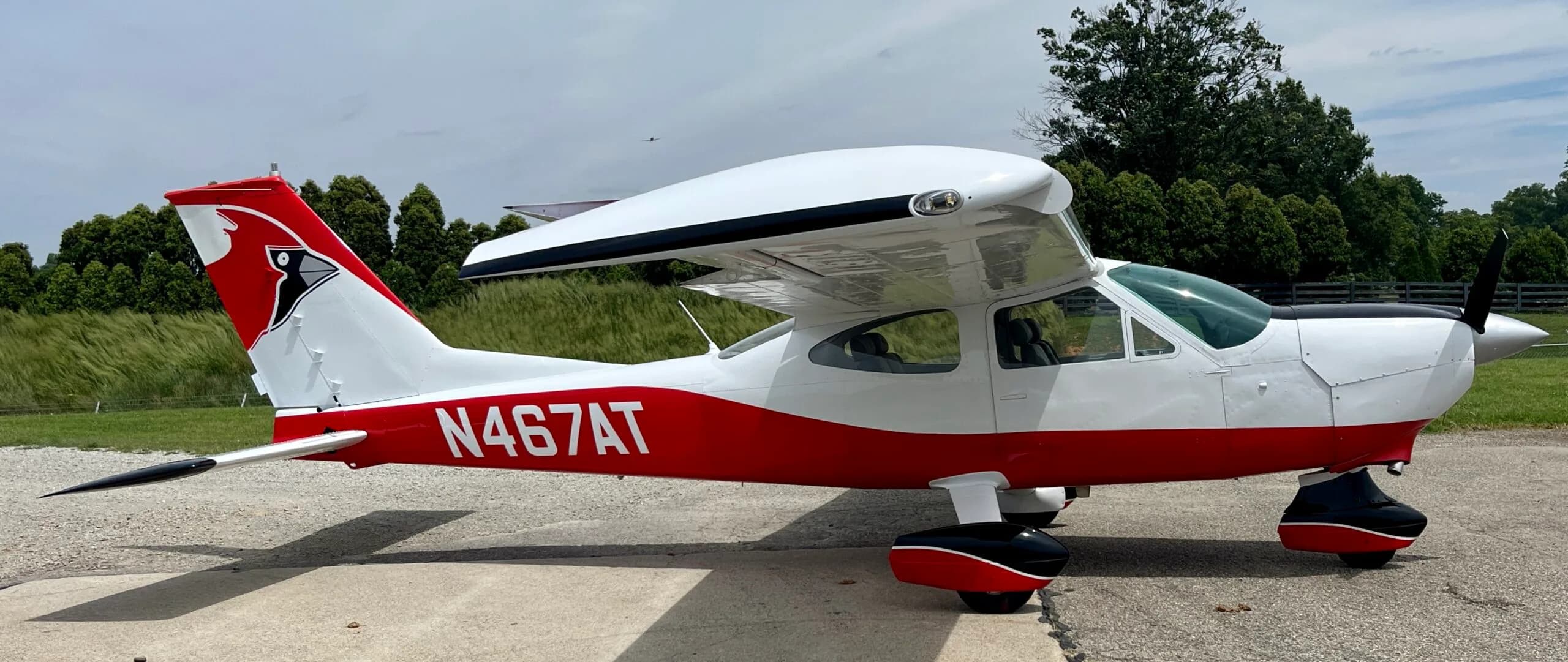 A red and white Cessna 182 Skylane with a cardinal logo on its tail, parked on an airfield.