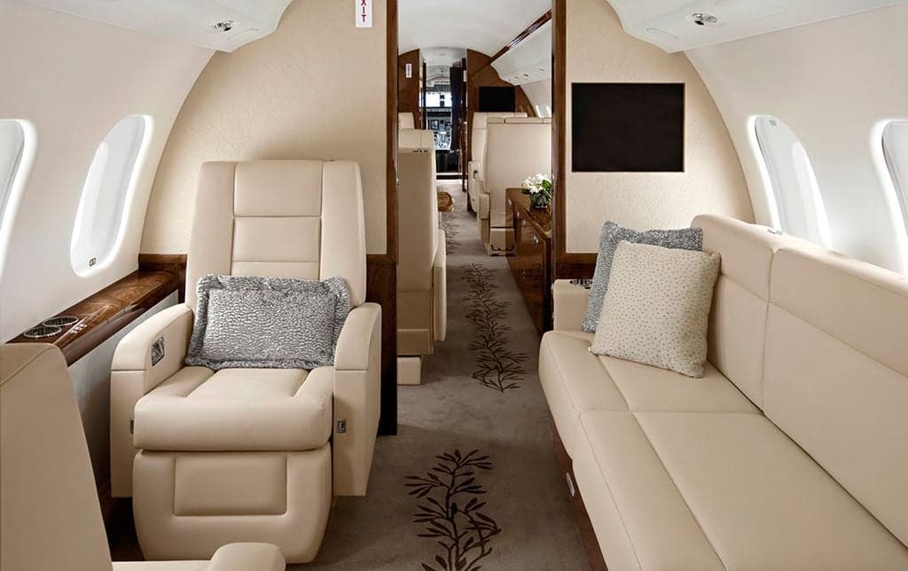 A luxurious aircraft interior with leather seats and a patterned carpet.