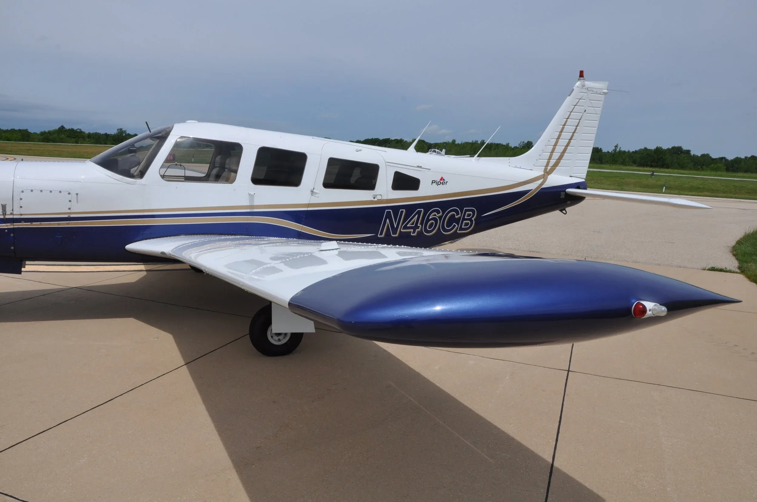 A close-up view of the tail and right wing of a white and blue Piper Lance aircraft (N46CB).