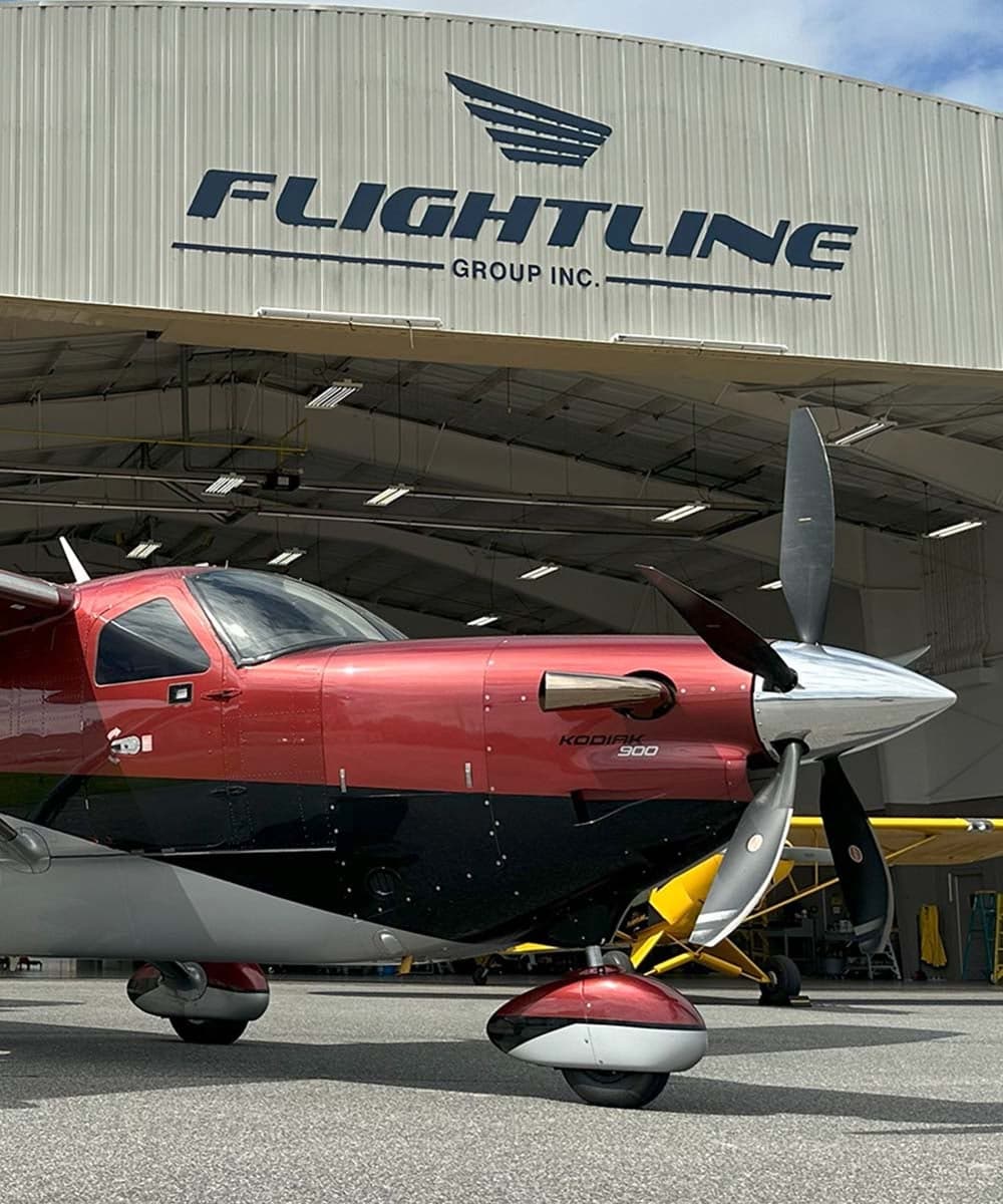 A Kodiak 900 parked in front of a Flightline Group hangar.
