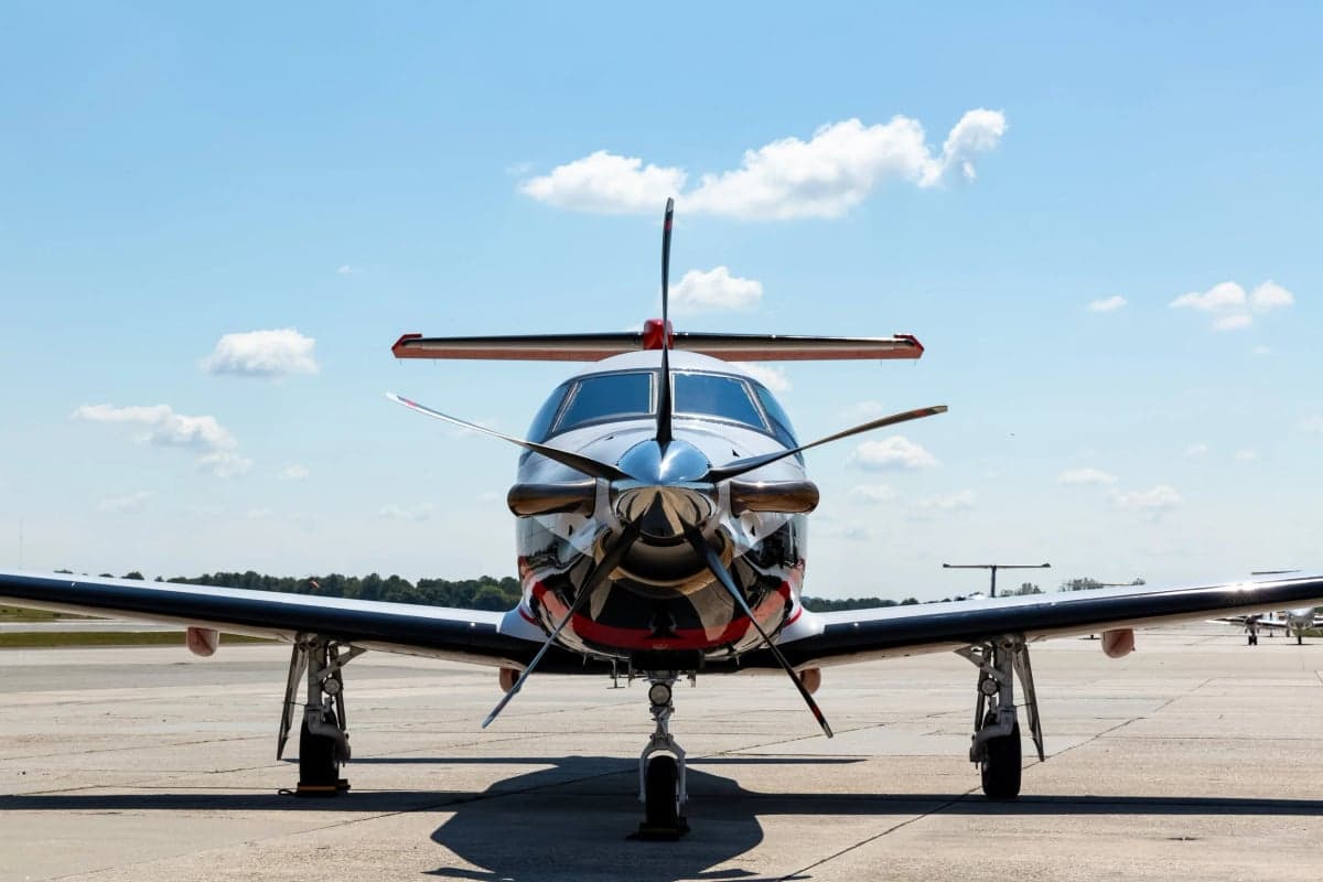 Front view of a Pilatus PC-12 on the tarmac with a black, white, and red paint scheme.