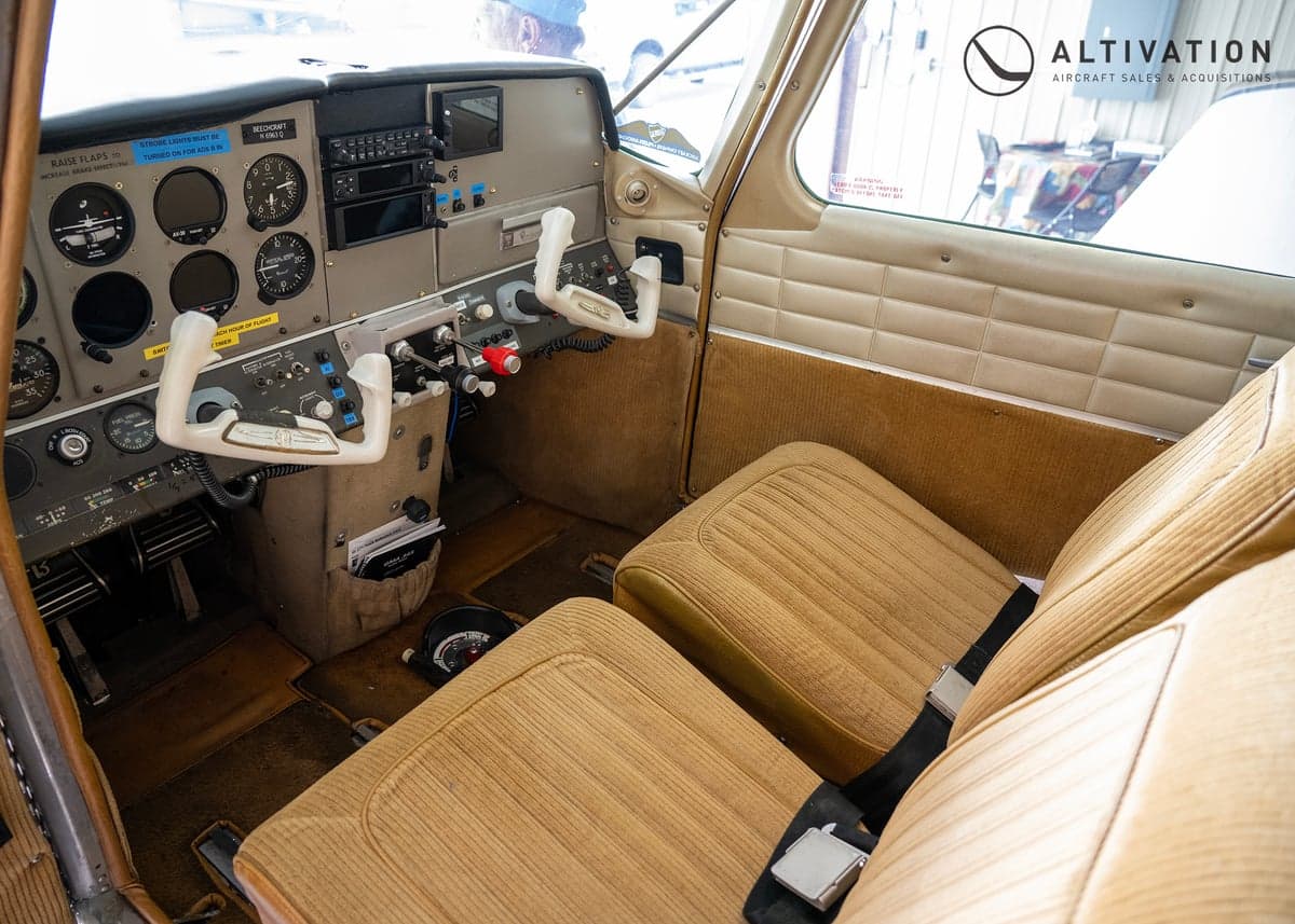 The cockpit of the Piper aircraft features a beige interior and a classic instrument panel.