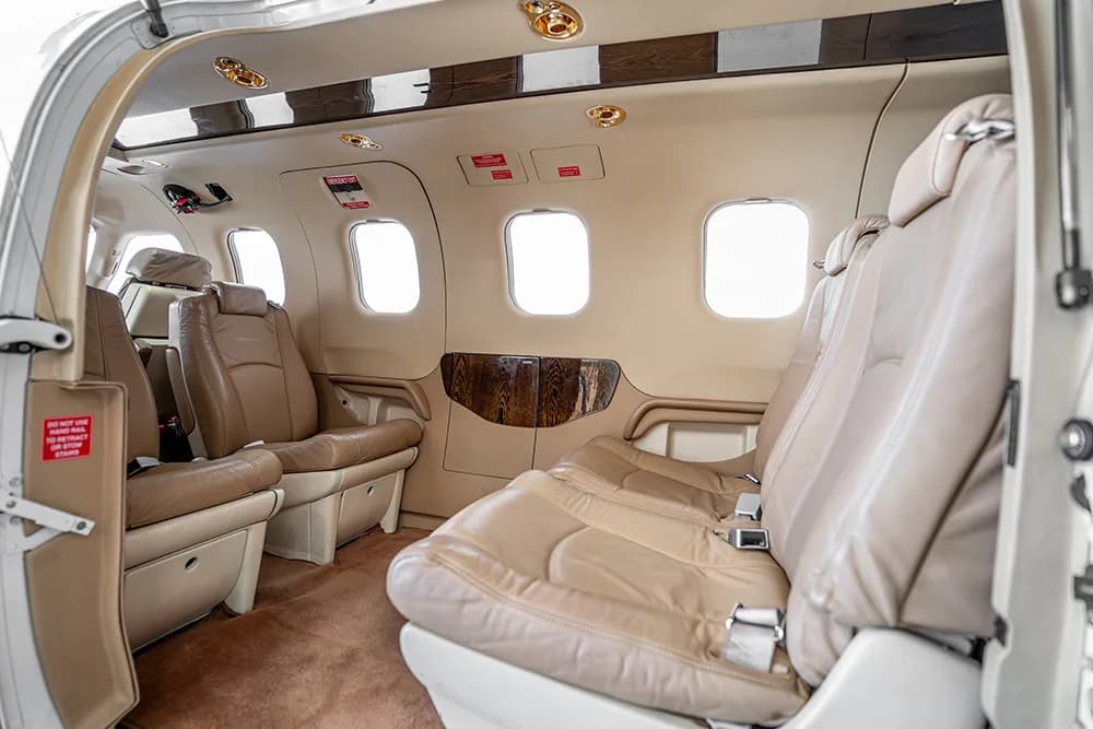 A side view of the aircraft cabin showing multiple light beige leather seats and windows.