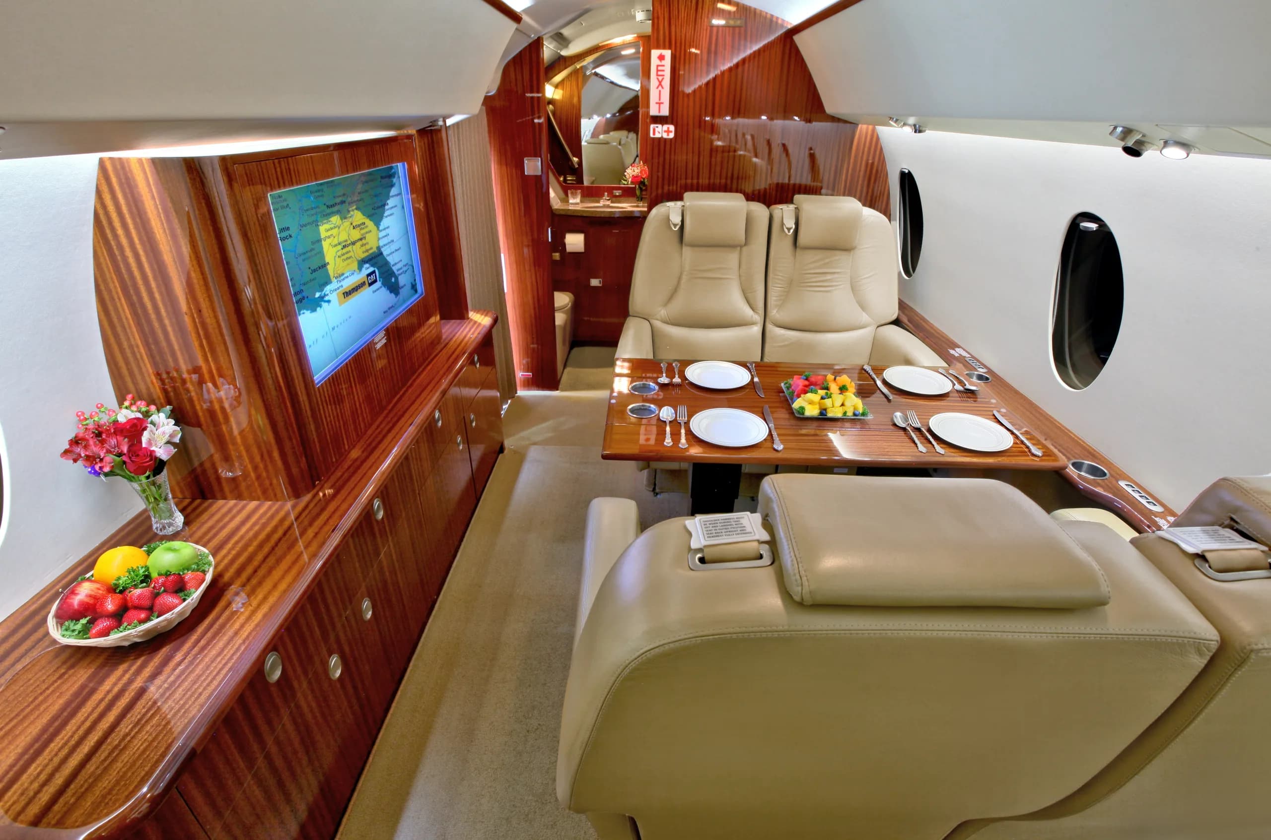 View of the aircraft's interior cabin with a dining table and entertainment system.