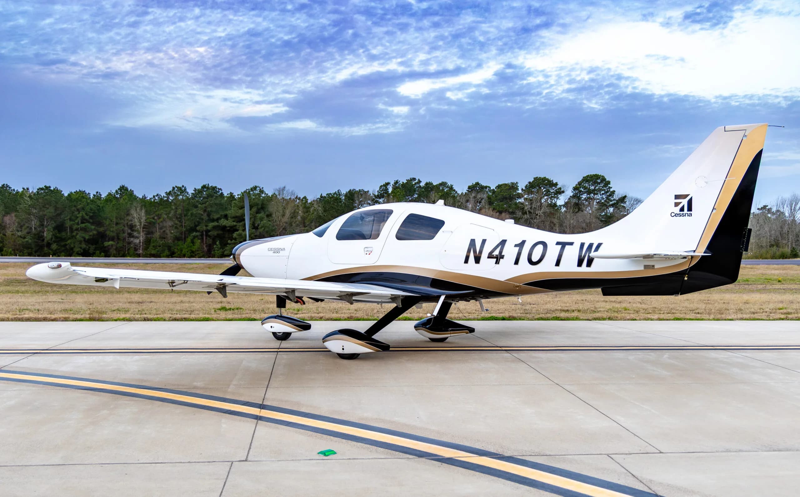 Cessna 400, registration N410TW, parked on the tarmac with a white and gold paint scheme.