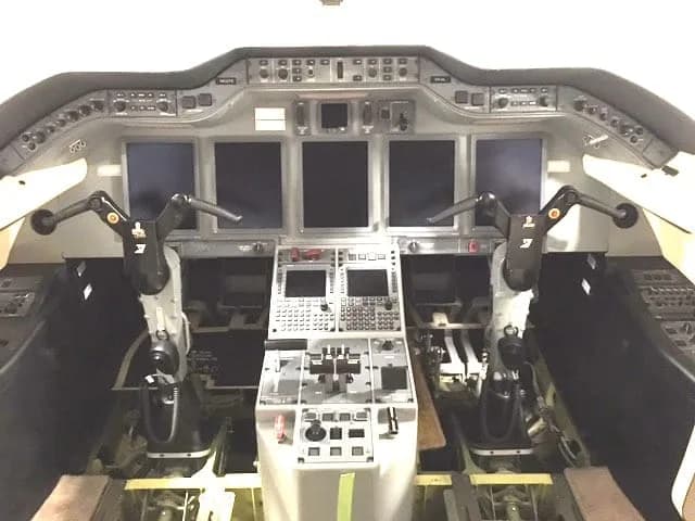The modern cockpit of a business jet features multiple digital displays and control yokes.