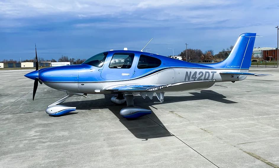 A Cirrus SR22T aircraft with a blue and silver paint scheme is parked on the tarmac.