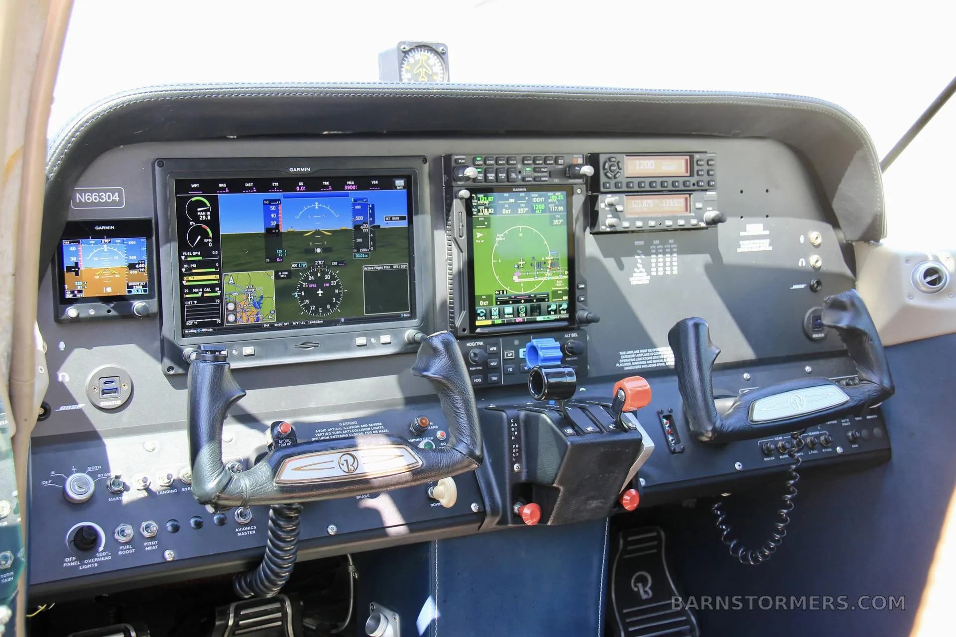 The cockpit of a small aircraft, featuring a modern Garmin glass panel display and traditional controls.