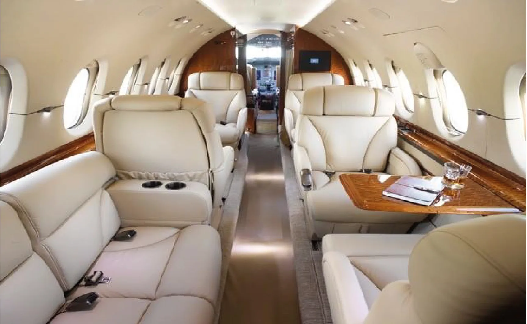 Aircraft interior with cream-colored leather seats and wood trim, looking towards the front.