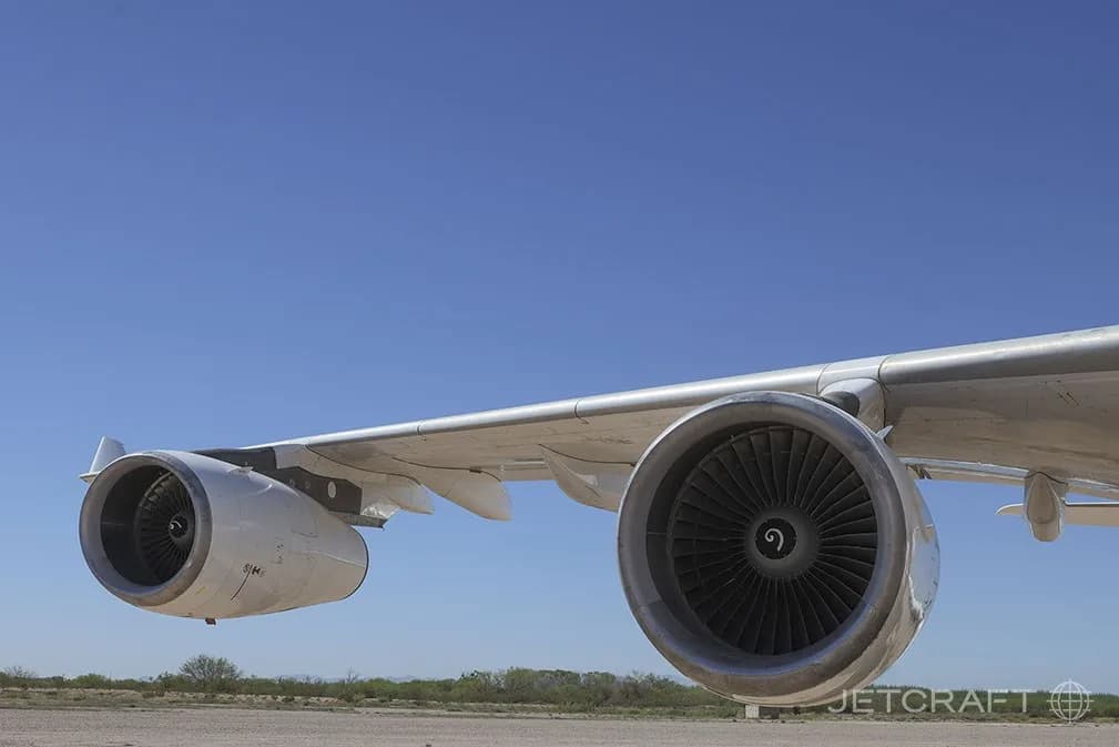 A close-up view of two engines and the wing of an Airbus A340-300 against a blue sky.