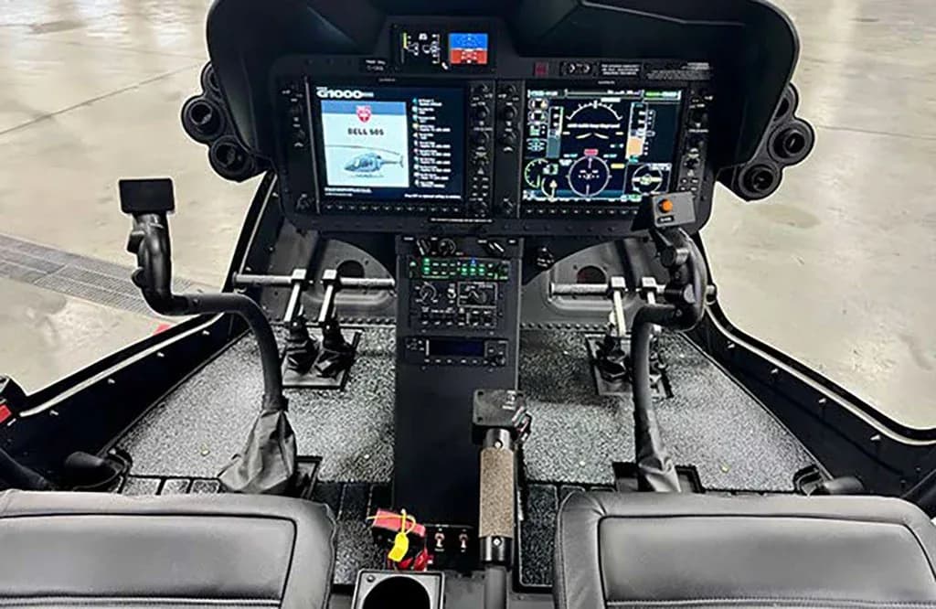 The modern cockpit of a Bell 505 helicopter features two large digital displays and dual controls.