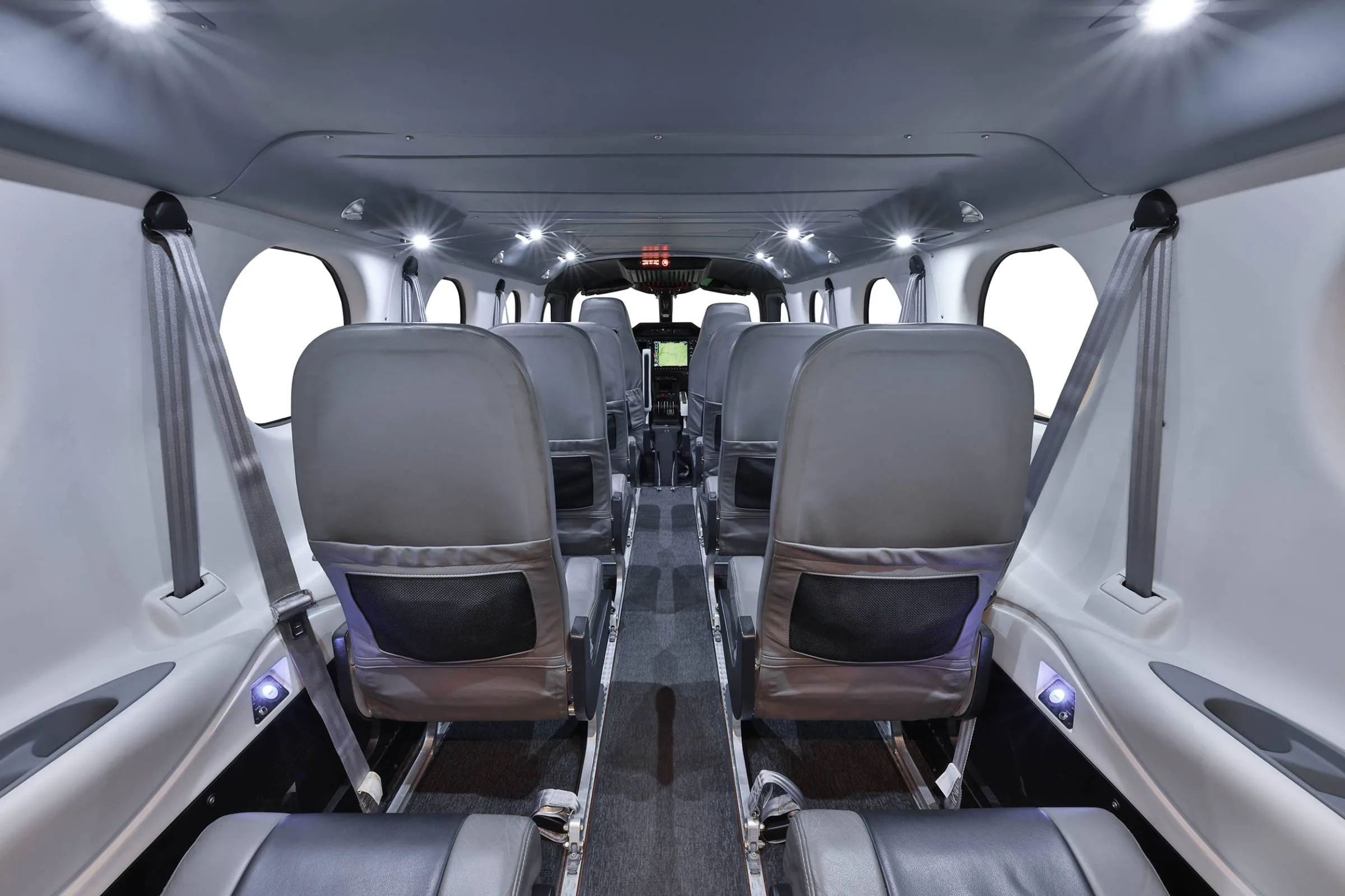 View down the aisle of the aircraft cabin with gray seats.