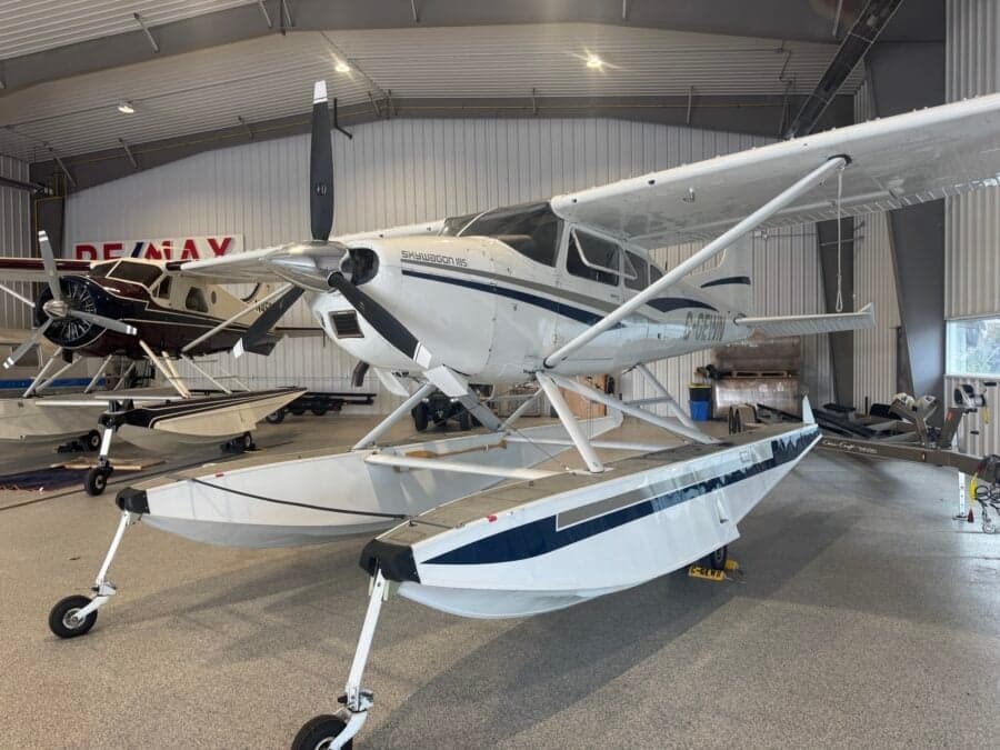 A Skywagon 185 floatplane is parked inside a hangar.
