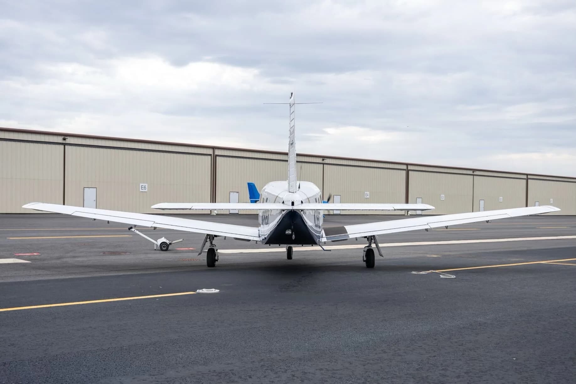 A rear view of a white Piper Saratoga II TC aircraft, tail number N269Z, parked on the tarmac in front of hangars.