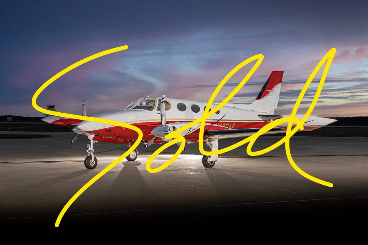 A Cessna 414 Chancellor aircraft on the tarmac at dusk, with a red and white paint scheme and the word 'SOLD' overlaid.
