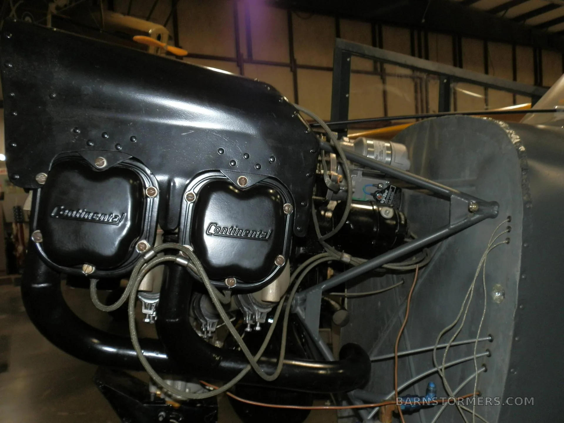 A close-up view of a black Continental aircraft engine with exposed cylinders and wiring.