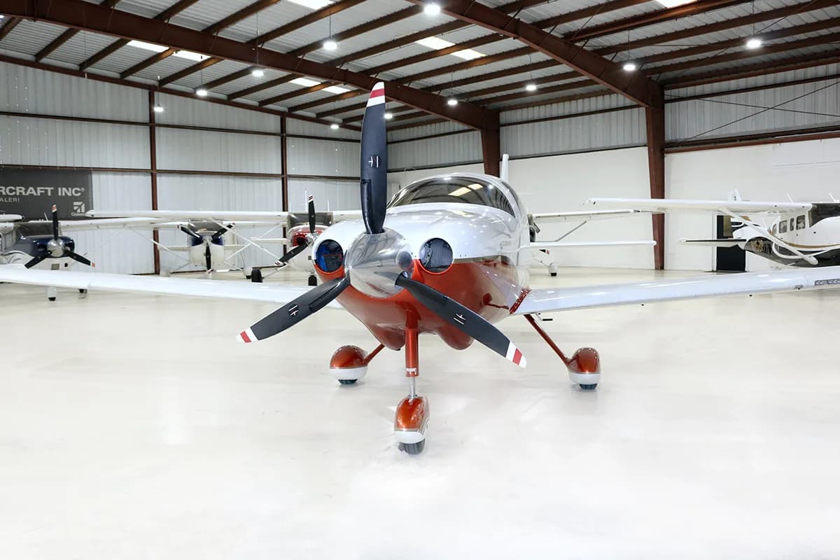 A front view of a white and red Columbia 400 aircraft with registration N7098C in a hangar.