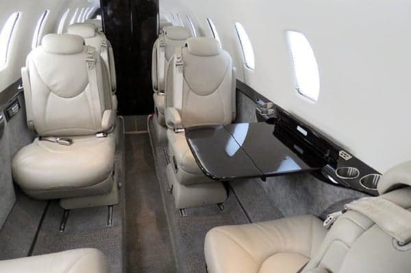 View of the aircraft's interior cabin with leather seats and a table.