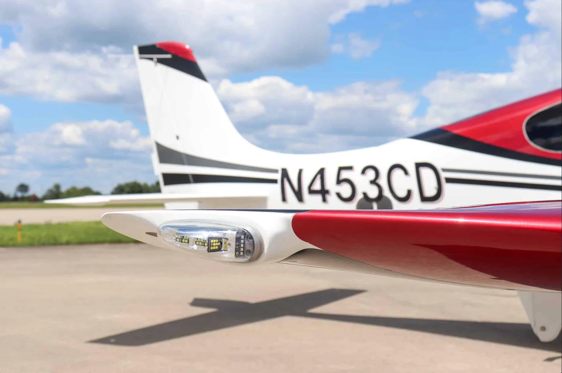A close-up view of the tail and wingtip light of a white and red aircraft with tail number N453CD.