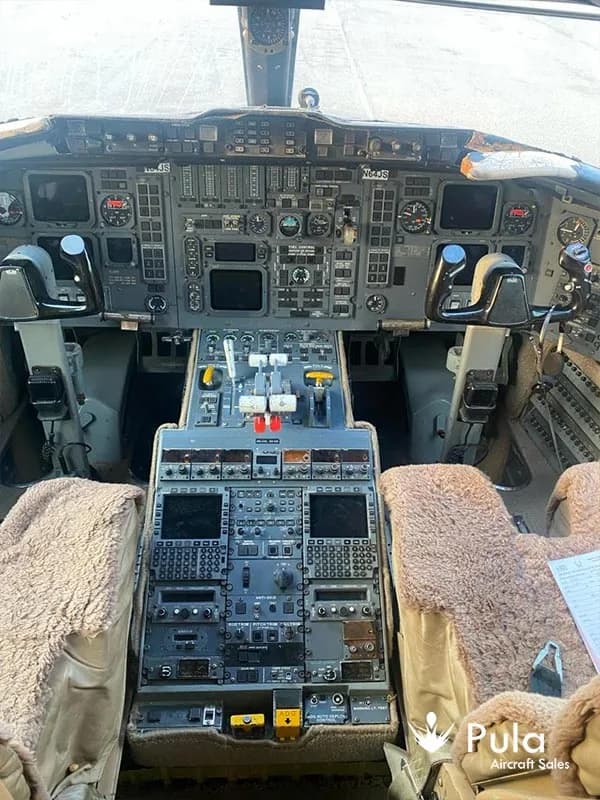 An overhead view of the Bombardier Challenger 604 (N64JS) cockpit, showing the main instrument panel and center console.