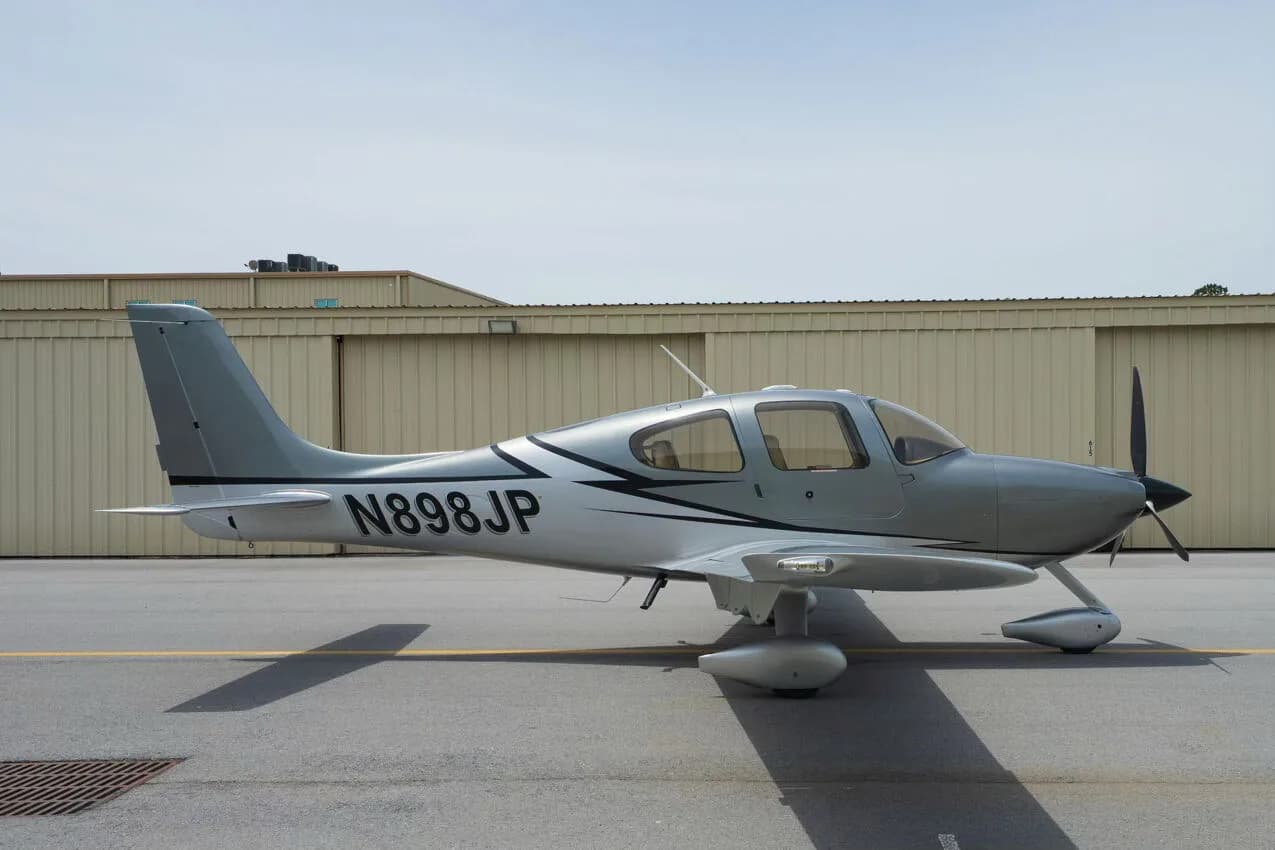 A silver Cirrus SR22 aircraft with black and white accents, registration N898JP, parked on an airfield.