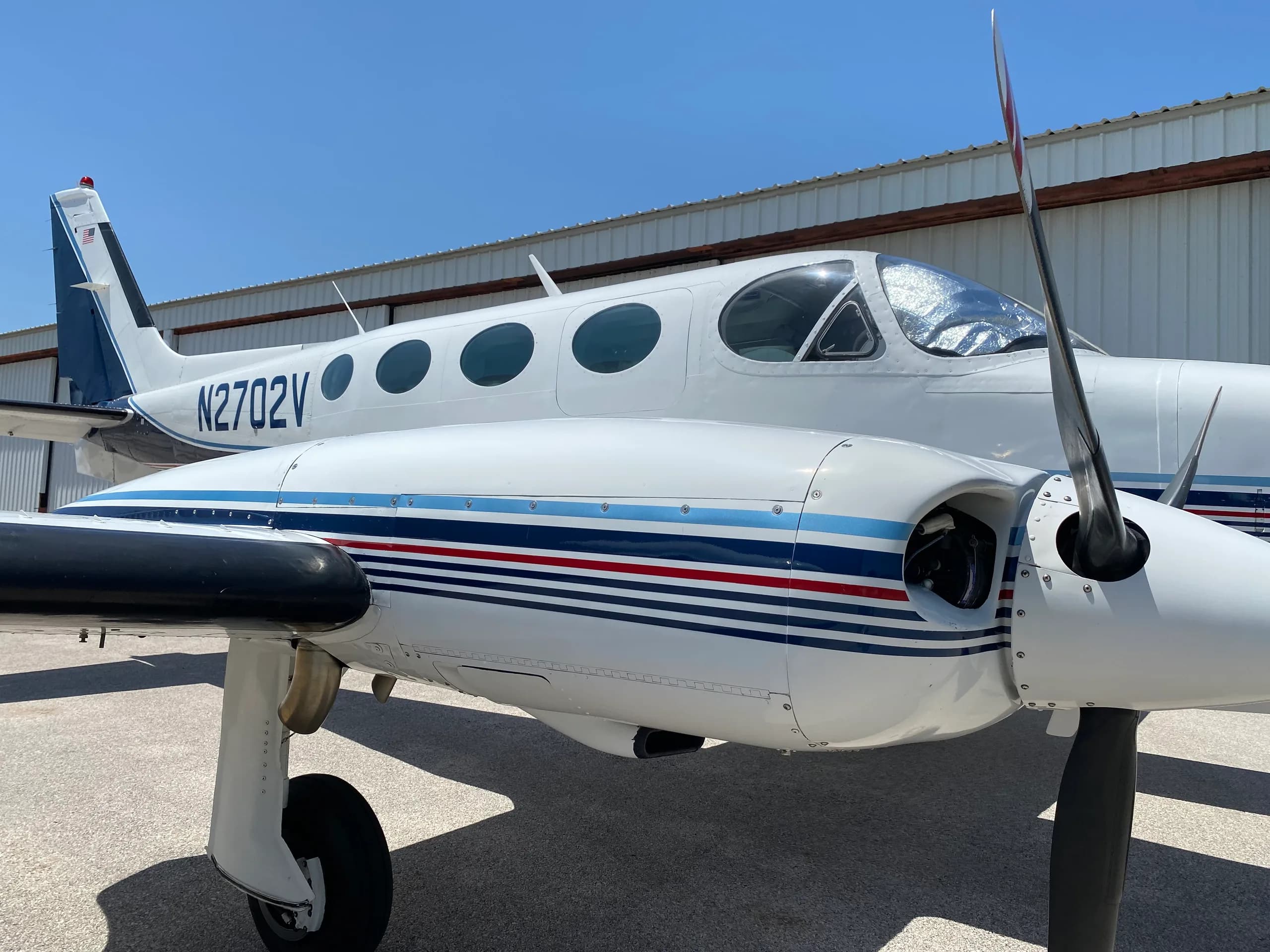 Close-up of the nose and engine of a Cessna 340A aircraft with registration N2702V.