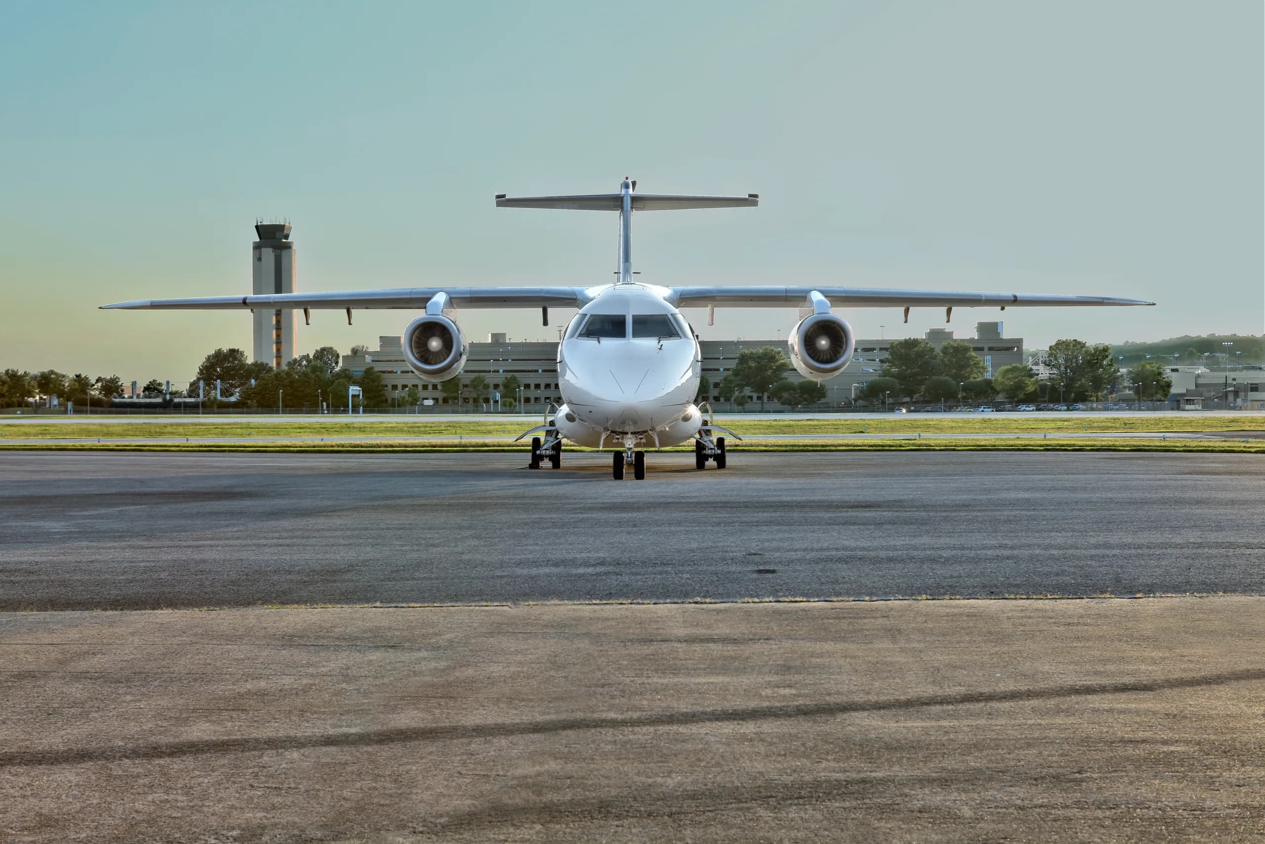Front view of the aircraft on the tarmac with a control tower in the background.