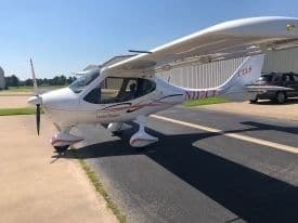 A white Cirrus aircraft with red accents is parked on the tarmac.