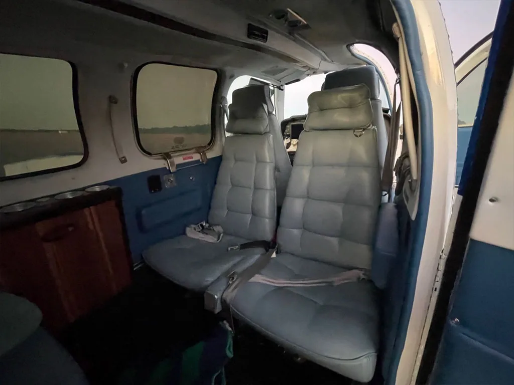 The aircraft's interior cabin features two rows of light blue upholstered seats.