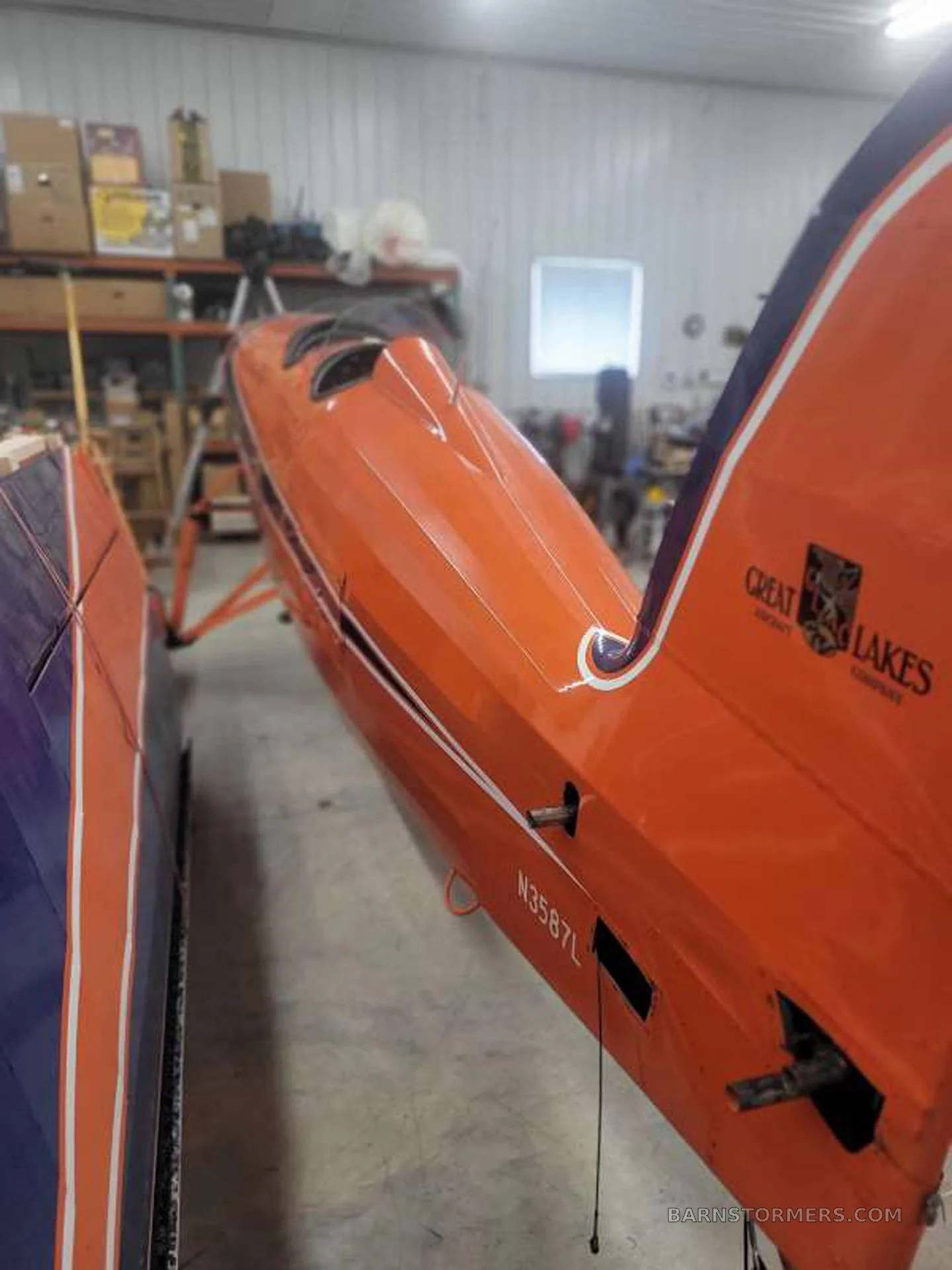A close-up of the orange aircraft's tail section, showing the registration N3587L and "Great Lakes Aircraft Company" logo.