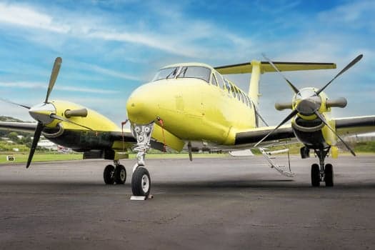 A yellow King Air on the tarmac with its landing gear visible.