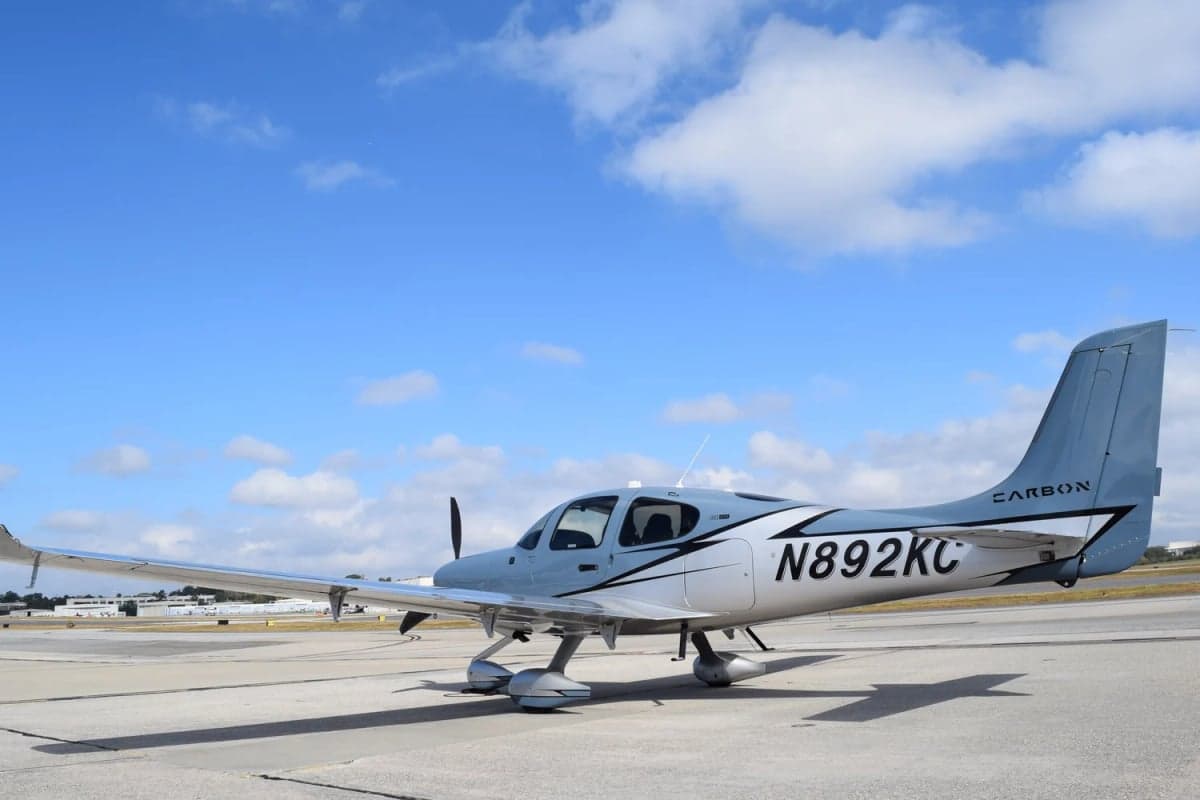 A Cirrus SR22T aircraft with a blue and silver paint scheme is parked on the tarmac.