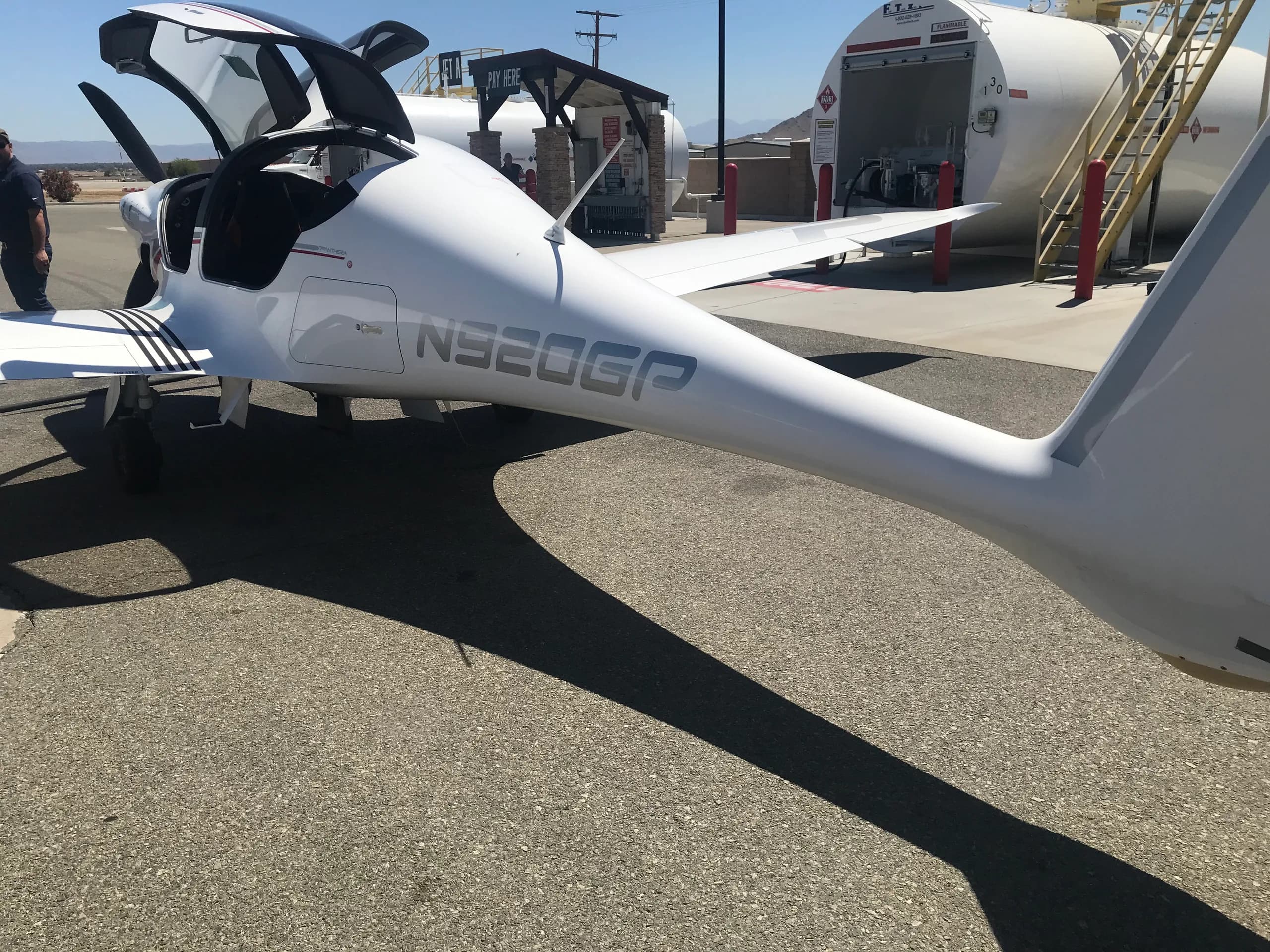 A white Pipistrel Panthera aircraft, registration N920GP, parked at an airfield fuel station with its canopy open.