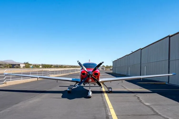 A head-on view of the red and silver Cirrus SR22T GTS Carbon aircraft parked on an airfield.