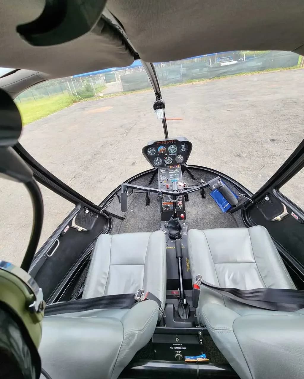 The gray leather front seats and instrument panel of a Robinson R44 helicopter, viewed from the rear cabin.