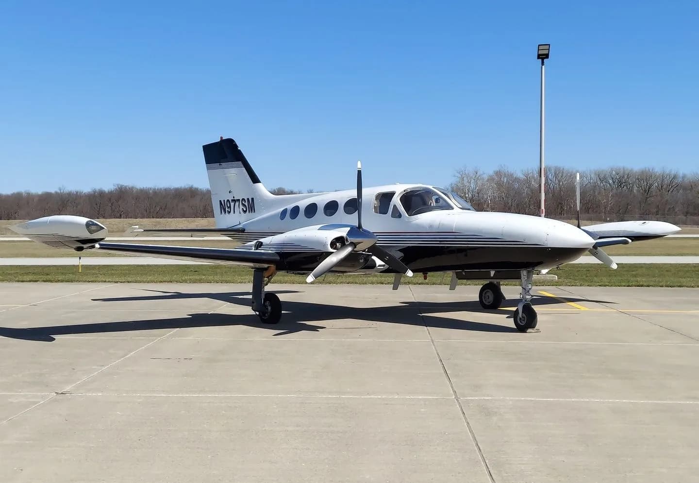 Side view of a Cessna 414 aircraft with registration N977SM parked on the tarmac.