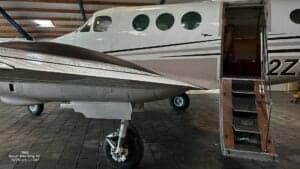 A Beech B90 King Air aircraft is shown with the entry door open.