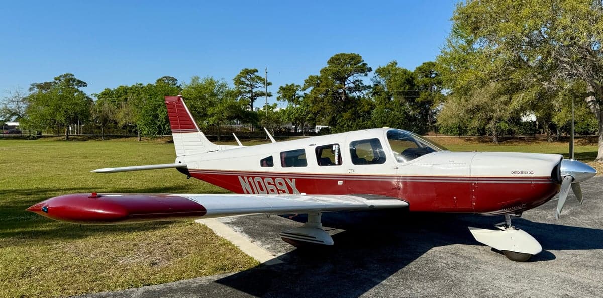 A Piper Cherokee PA-28-181 Archer II aircraft with registration N1069X, parked on a grassy area.