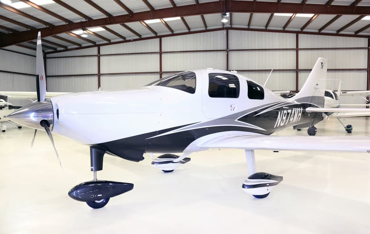 A Cirrus SR22T aircraft with registration N974MH is parked inside a hangar.