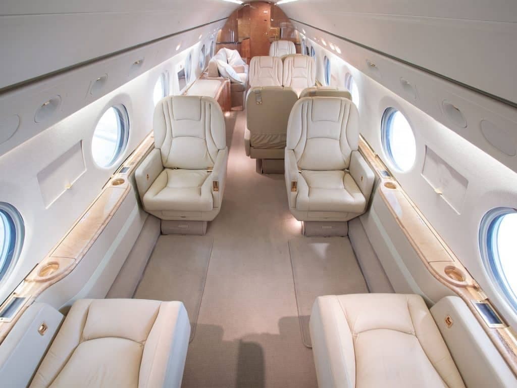 Aircraft interior featuring leather seats and oval windows.