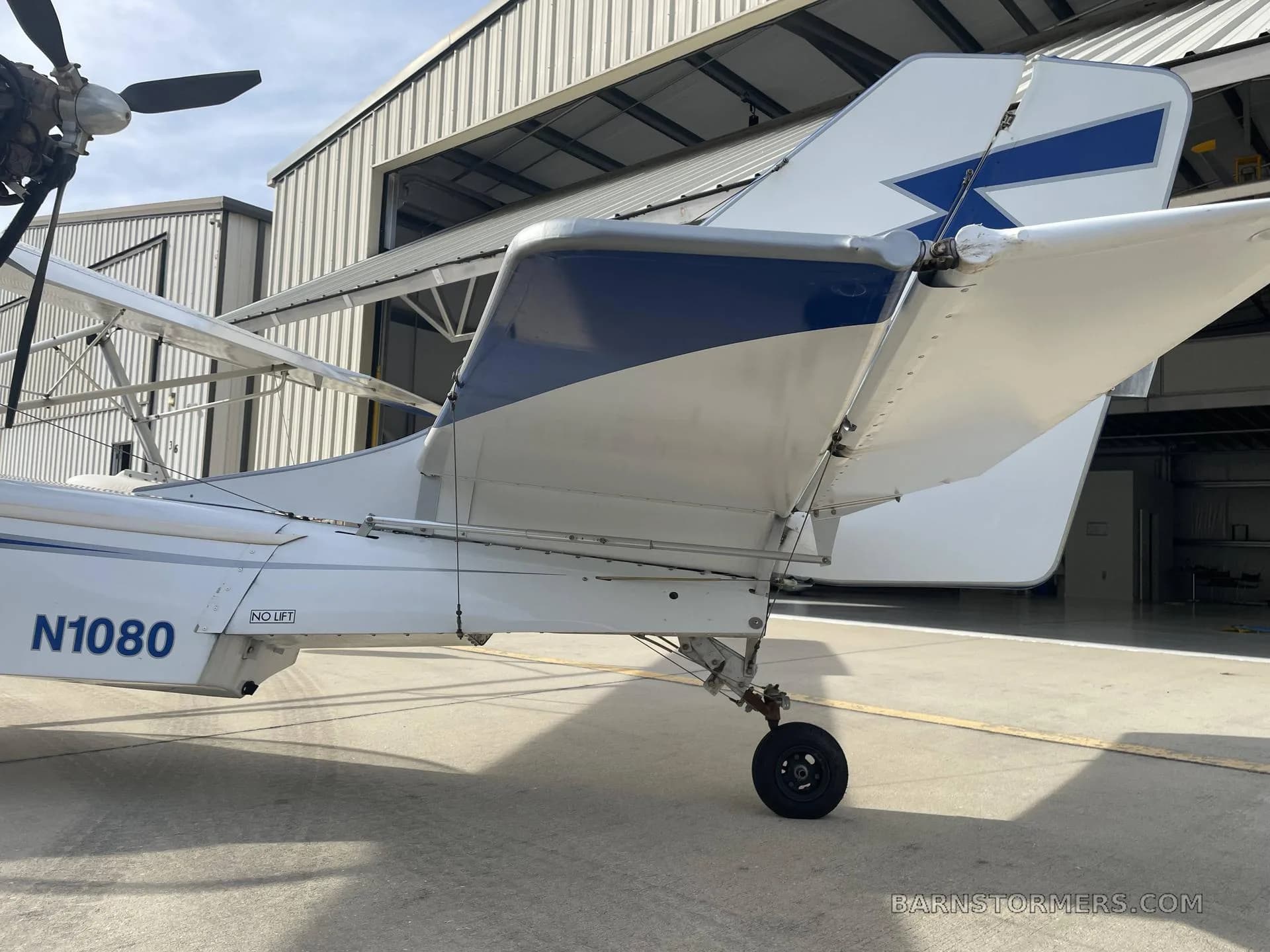 A close-up view of the tail and rear landing gear of a white and blue Searey aircraft (N1080).