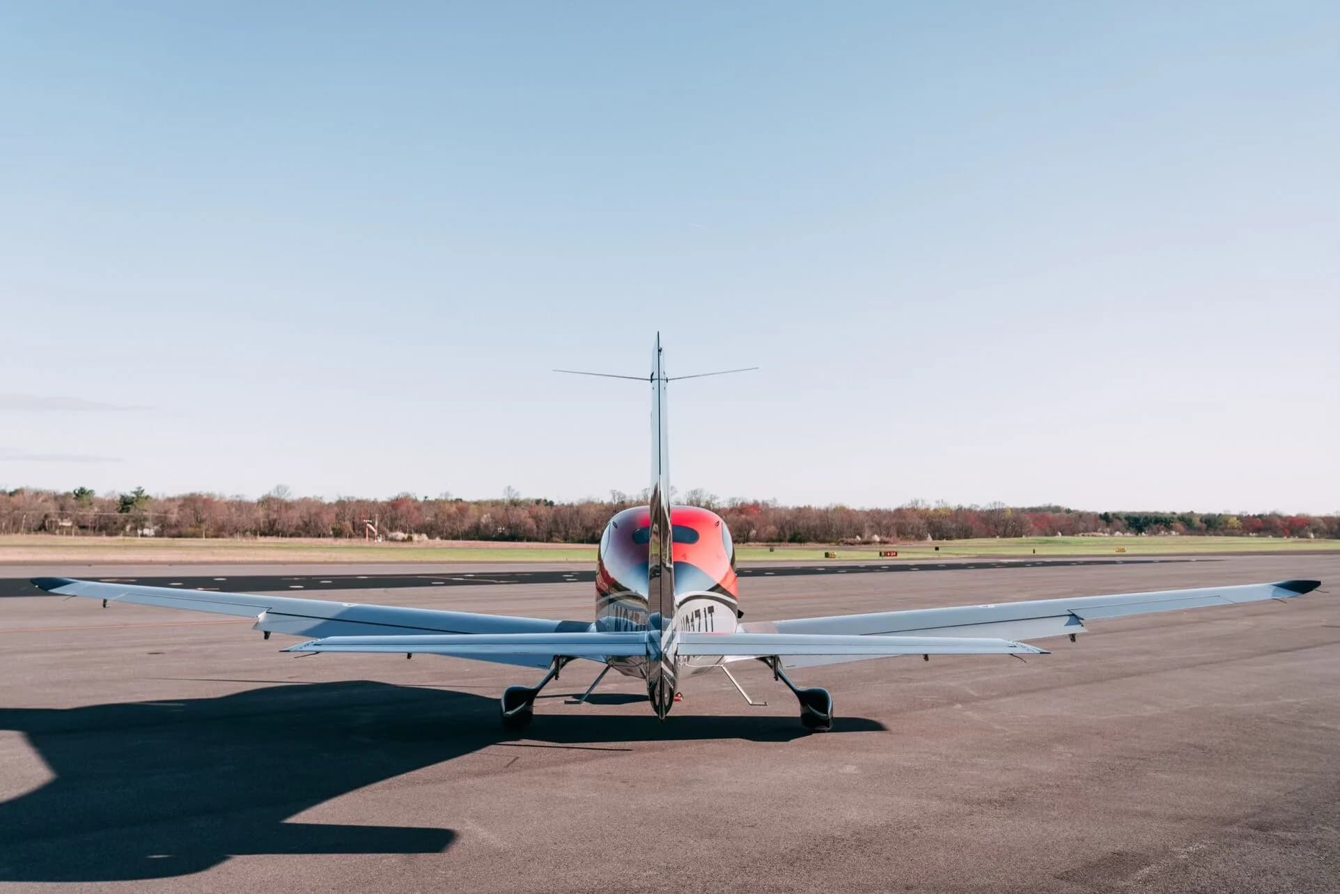 A rear view of the red, black, and silver Cirrus SR22T aircraft parked on an asphalt tarmac.