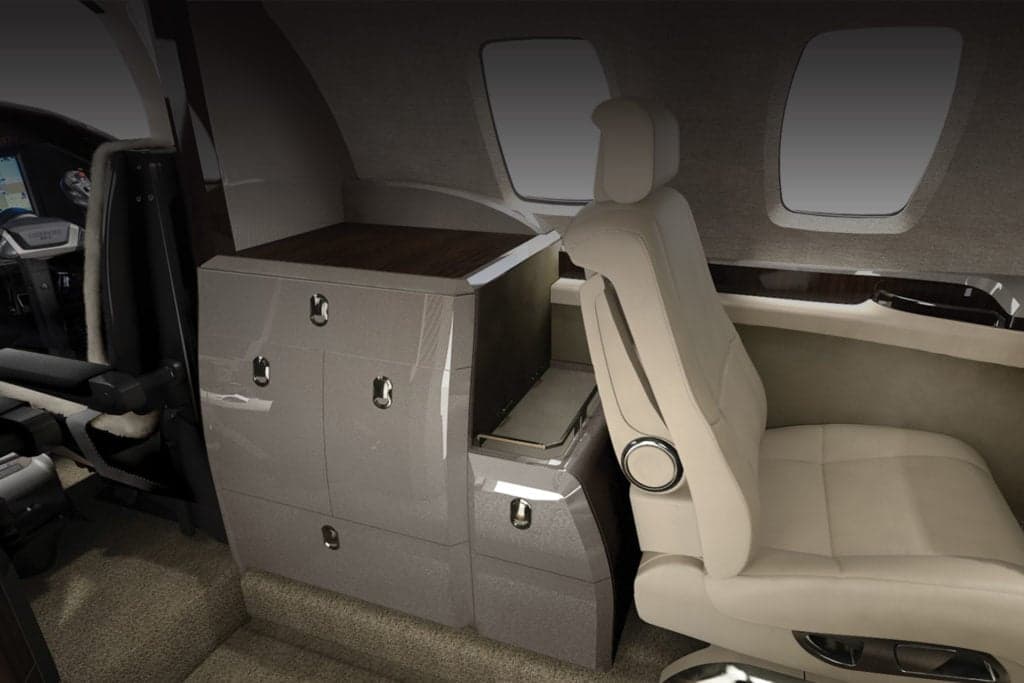 The interior of a Citation M2 aircraft with a cabinet and seat.